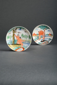 Lot 345 - Two Chinese porcelain Dutch-decorated saucers  1st half 18th century, originally left in the white and later-enamelled in Holland, one with a scene of Adam and Eve beneath the Tree of Knowledge, the serpent offering the apple to Eve while birds fly above, the other decorated with a tall dovecote beneath a tree, a church and other European buildings beyond, 11cm. (2) Provenance: the Helen Espir Collection, nos. 896 and 925. Illustrated: Helen Espir, European Decoration on Oriental Porcelain, p.197, pl.54 for the Adam and Eve saucer. The enamel palette of both saucers is distinctly Dutch, and the subject of the first couple a traditional theme for Delft chargers. Estimate: £600 – 1000 